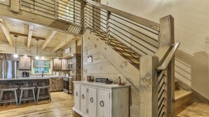 A spacious kitchen with wooden beams, a central island, and a white cabinet. - Knotty by Nature | Cherry Log Mountain Cabin (Blue Ridge)