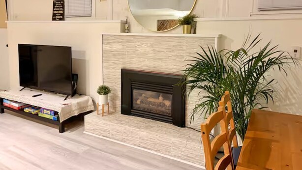 A living room with a fireplace, a television, and a large mirror on the wall. - Entire guest suite in Delta, Canada, Cozy & Stylish 1BR Perfect for Getaways (Delta)