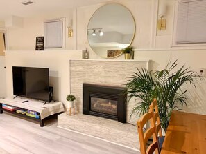 A living room with a fireplace, a television, and a large mirror on the wall. - Entire guest suite in Delta, Canada, Cozy & Stylish 1BR Perfect for Getaways (Delta)