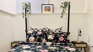 A bed with a floral bedspread, two nightstands with lamps, and hanging plants. - Entire guest suite in Delta, Canada, Cozy & Stylish 1BR Perfect for Getaways (Delta)