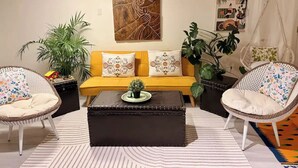 A living room with a yellow sofa, two wicker chairs, a black ottoman, and a striped rug. - Entire guest suite in Delta, Canada, Cozy & Stylish 1BR Perfect for Getaways (Delta)
