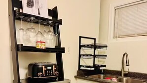 A compact kitchen with a built-in microwave, a toaster, and a shelf with glassware and a decorative item. - Entire guest suite in Delta, Canada, Cozy & Stylish 1BR Perfect for Getaways (Delta)