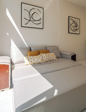 Une chambre à coucher moderne avec un lit, des oreillers et deux œuvres d’art abstraites accrochées au mur.