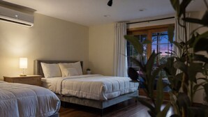 Un dormitorio con dos camas, una mesita de noche, una lámpara y una ventana con cortinas.