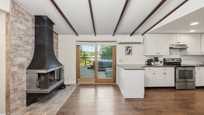 Una cocina con chimenea de piedra, armarios blancos y horno de acero inoxidable.