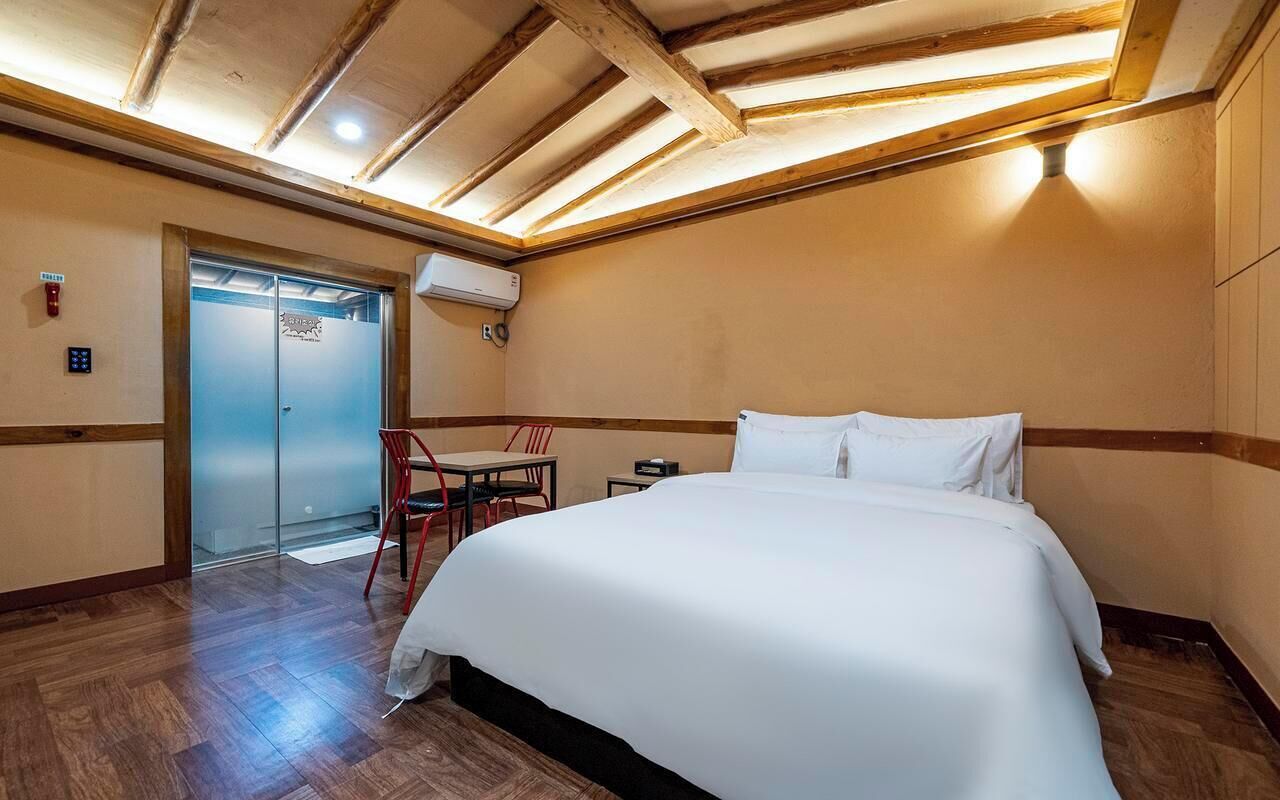 Hotellihuone, jossa on sänky, työpöytä, tuoli ja ovi.