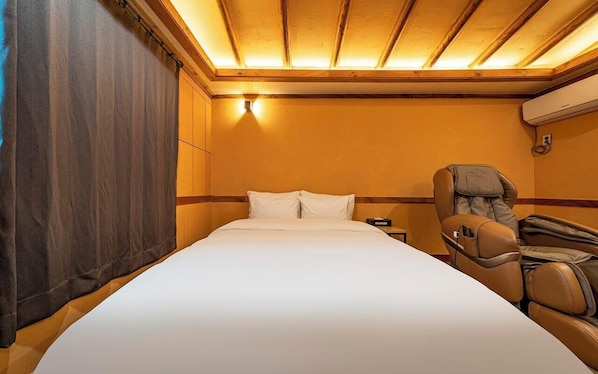 Hotellihuone, jossa on suuri sänky, hierontatuoli ja puinen katto.