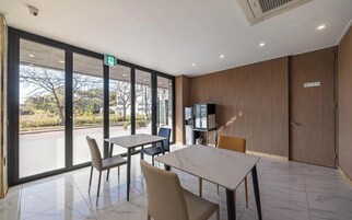 Una habitación de hotel moderna con un ventanal grande, un televisor de pantalla plana y una zona de comedor con mesa y sillas.