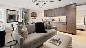 A modern living room with a grey sofa, a coffee table, and a dining area with a black table and chairs. - Ski-In Aspen Retreat Next To Lift 1A with Fireplace & Walkable Downtown Access (Aspen)