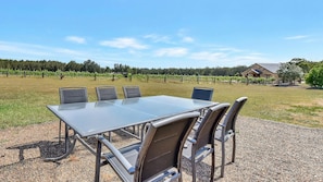 A table with chairs set outdoors, a gravel ground, and a vineyard in the background. - Shiraz Vineyard Estate (Pokolbin)