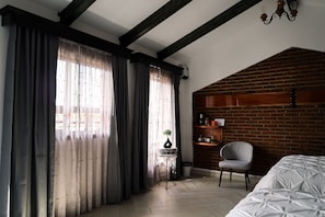 A room with a bed, a chair, a small table with a plant, and a brick wall. - Hotel Royal Inglés (Mineral del Monte)
