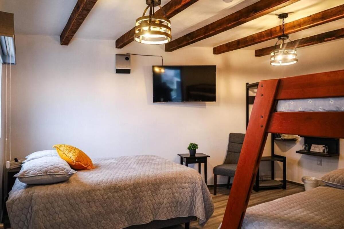 Ein Schlafzimmer mit einem Bett, einem Fernseher, einem Sessel und einem hölzernen Kopfteil.
