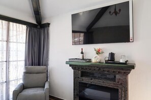 A room with a fireplace, a mounted TV, and a window with curtains. - Hotel Royal Inglés (Mineral del Monte)