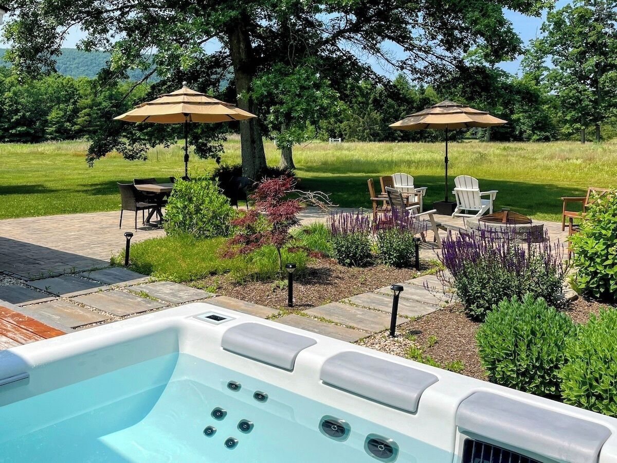 Un jacuzzi dans un jardin, avec des meubles de patio et des parasols.