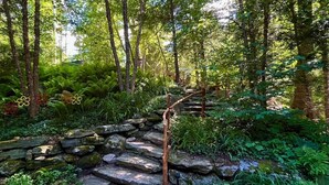 A stone pathway leading through a forested area with a wooden bridge over a small stream. - Direct on Lake Garfield: Book Fall Weekends! (Monterey)