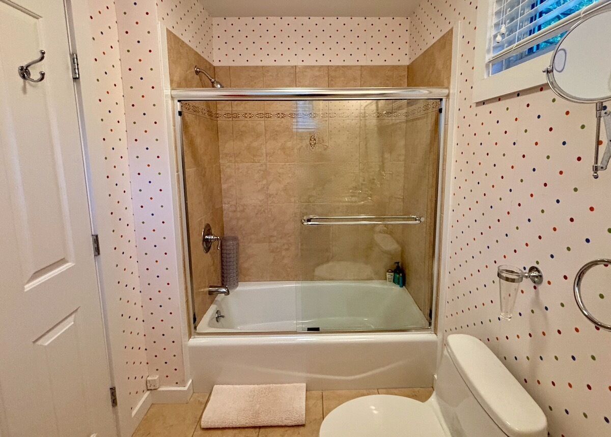 A bathroom with a glass-enclosed shower, a white toilet, and a bathtub.