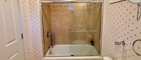 A bathroom with a glass-enclosed shower, a white toilet, and a bathtub.