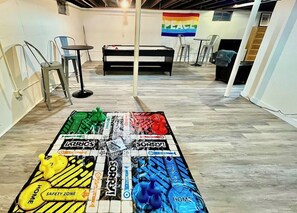 A pool table in a room with a 'PEACE' flag on the wall, metal chairs, and a 'SAFETY ZONE' sign on the table.