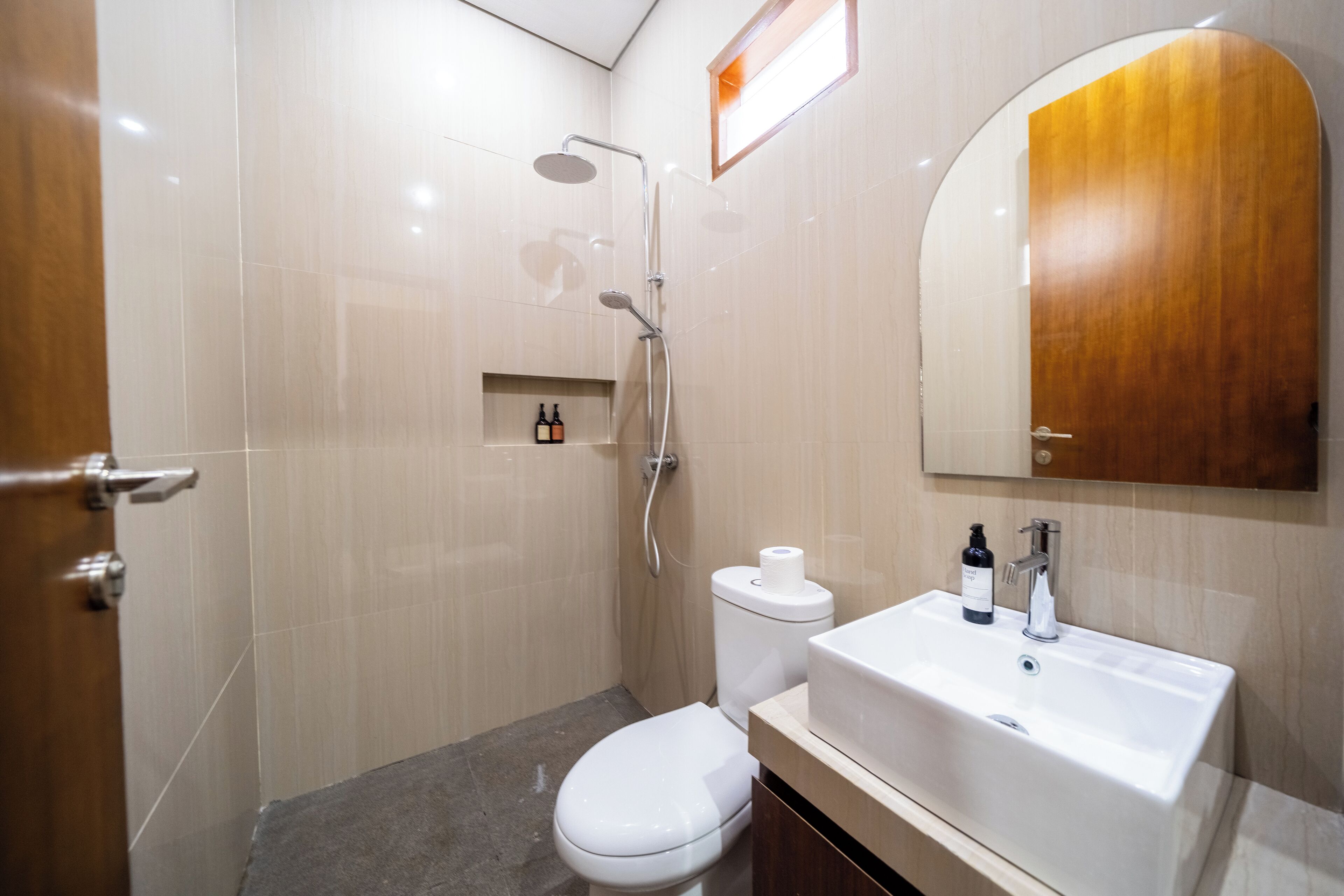 Ein modernes Badezimmer mit Toilette, Waschbecken mit Spiegel und Duschbereich.