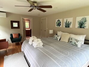 A bedroom with a large bed, a ceiling fan, a chair, and a door leading to another room. - Fall Weekends: Hot Tub, Green River Hike, Sleeps 10 (Great Barrington)