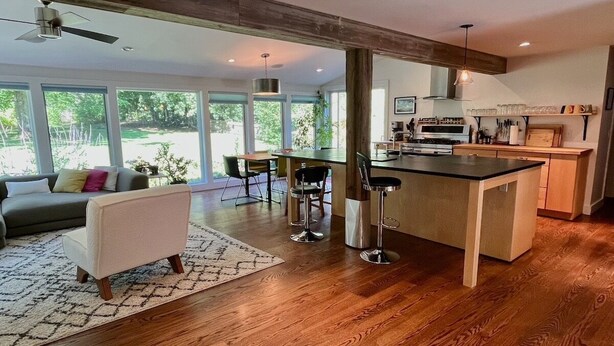 A spacious living area with a wooden floor, a sofa, a coffee table, and a bar area with stools.