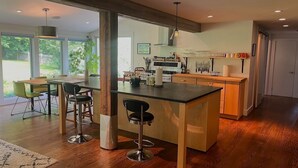 A modern kitchen with a central island, bar stools, and a dining area with a table and chairs.