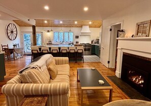 A cozy living room with a sofa, a coffee table, and a fireplace. - Light-filled, Stylish, Farmhouse Colonial, Egremont MA (Egremont)