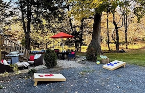 An outdoor patio area with a grill, seating, and a red umbrella. - Light-filled, Stylish, Farmhouse Colonial, Egremont MA (Egremont)