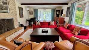 Ein geräumiges Wohnzimmer mit Ledersofas, einem Couchtisch in der Mitte und einem Klavier.