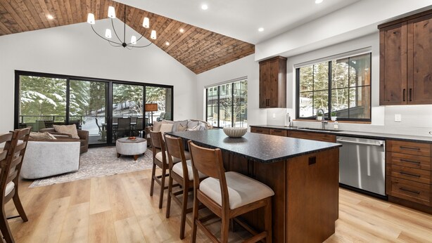Una cocina moderna con una isla grande, armarios de madera y una zona de comedor con sillas y un sofá.
