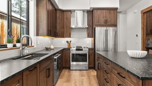 Una cocina moderna con armarios de madera, electrodomésticos de acero inoxidable y una encimera de granito.