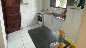 A compact kitchen with white cabinets, a built-in oven, a sink, and a window with a view of greenery outside. - Pet-Friendly Home (Guarapari)