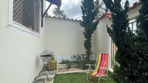 A backyard with a lawn, a grill, a chair, and a gas cylinder. - Pet-Friendly Home (Guarapari)