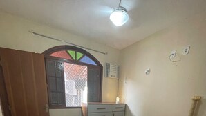 A bedroom with a bed, a nightstand, a dresser, a window with a decorative frame, and a ceiling fan. - Pet-Friendly Home (Guarapari)