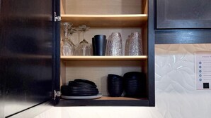 Una cucina con uno scaffale in legno, un calendario e una pianta in vaso.
