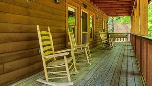 Eine hölzerne Veranda mit Schaukelstühlen und einer Bank, Holzfassade und eine Holzterrasse.