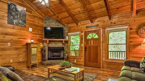 Ein Holzblockhaus-Interieur mit Kamin, Fernseher und einer Couch.
