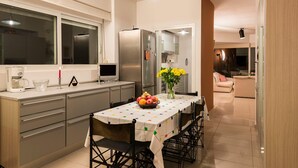 Uma cozinha moderna com eletrodomésticos de aço inoxidável, uma mesa de jantar com toalha de mesa colorida e um vaso de flores amarelas.