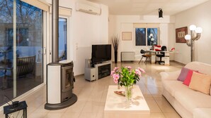 Uma sala de estar moderna com lareira, televisão, área de refeições e sofá.