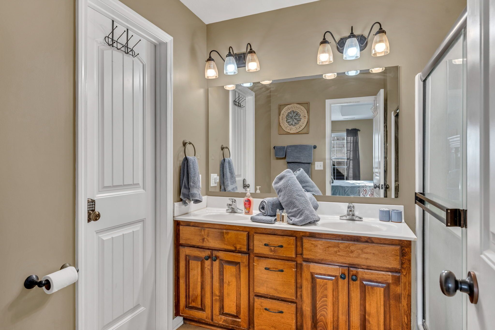 A bathroom with wooden cabinets, a white sink, and a large mirror.