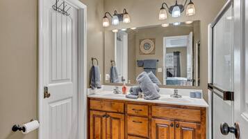 A bathroom with wooden cabinets, a white sink, and a large mirror.