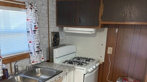 A compact kitchen with a gas stove, double sink, and wooden cabinets. - Property Rental 699 Per Week + Boat Rental 799 Per Week + Fees (Barnett)