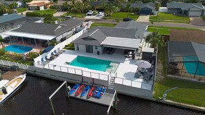 Propiedad frente al agua con piscina, patio cubierto y muelle con kayaks.