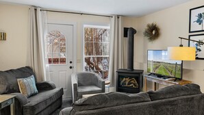 Een knusse woonkamer met een open haard, een televisie en een comfortabele zithoek.