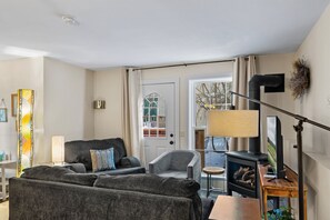 Un salon chaleureux avec un canapé, un fauteuil et une cheminée.