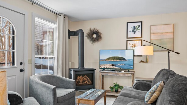Een gezellige woonkamer met een open haard, comfortabele zithoek, een televisie en kunst aan de muur.
