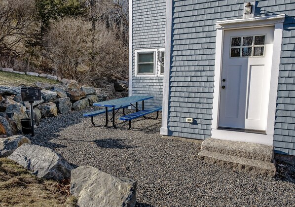 A building with a white door, a small window, and a gravel driveway.