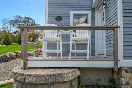 A deck with two white chairs and a stone base.