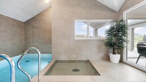 A modern indoor pool area with a clear view of the sky through a large window, a built-in hot tub, and a potted plant. - VillaVilla 929 - Hvide Sande, Vestjylland (Hvide Sande)