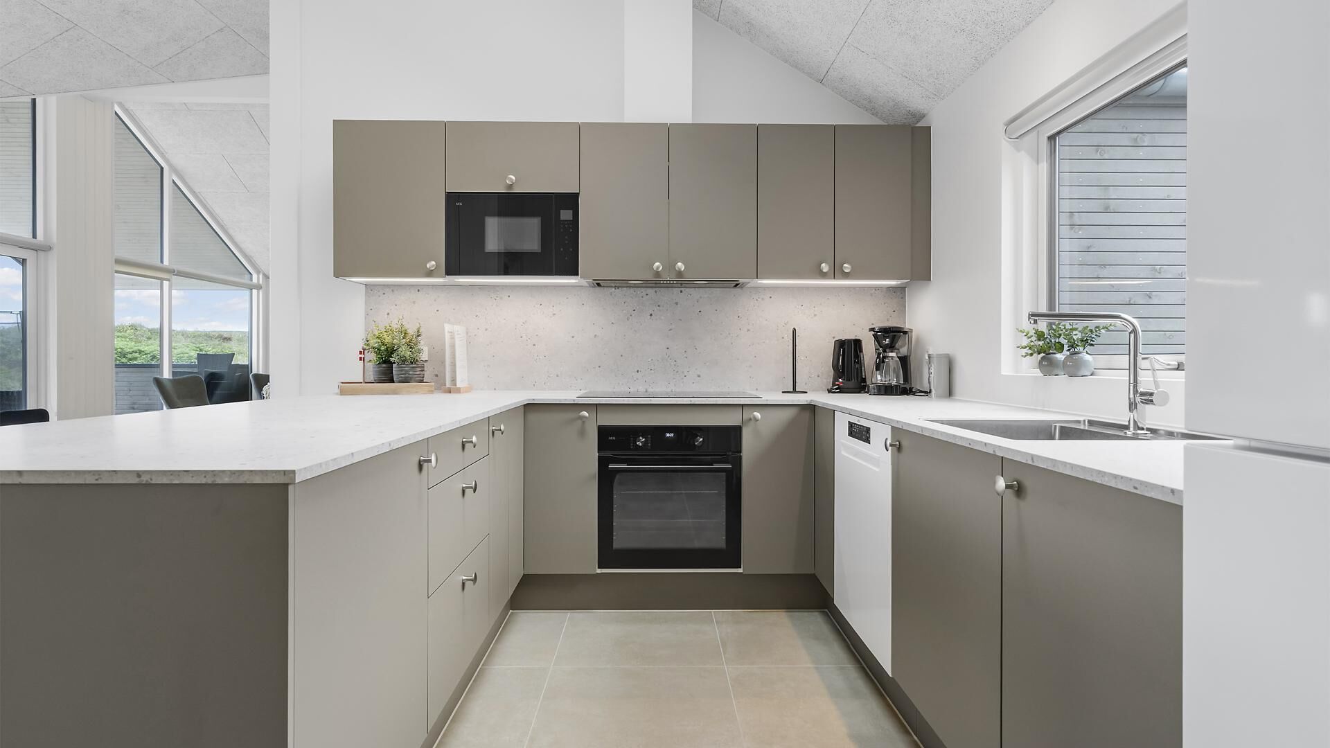 Una cocina moderna con horno integrado, cafetera y ventana que proporciona luz natural.